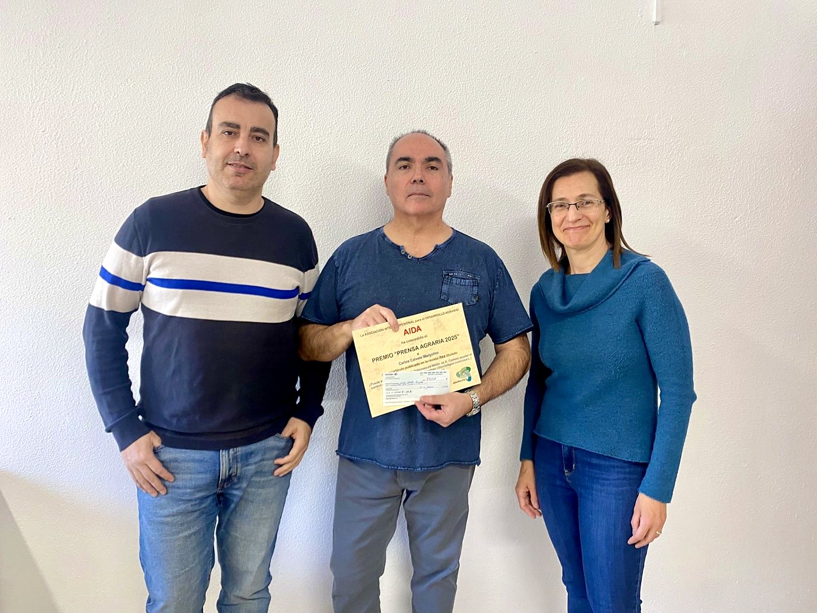 Guillermo Ripoll, tesorero de AIDA, Carlos Calvete, con el diploma del Premio Prensa Agraria 2025, y Albina Sanz, presidenta de AIDA